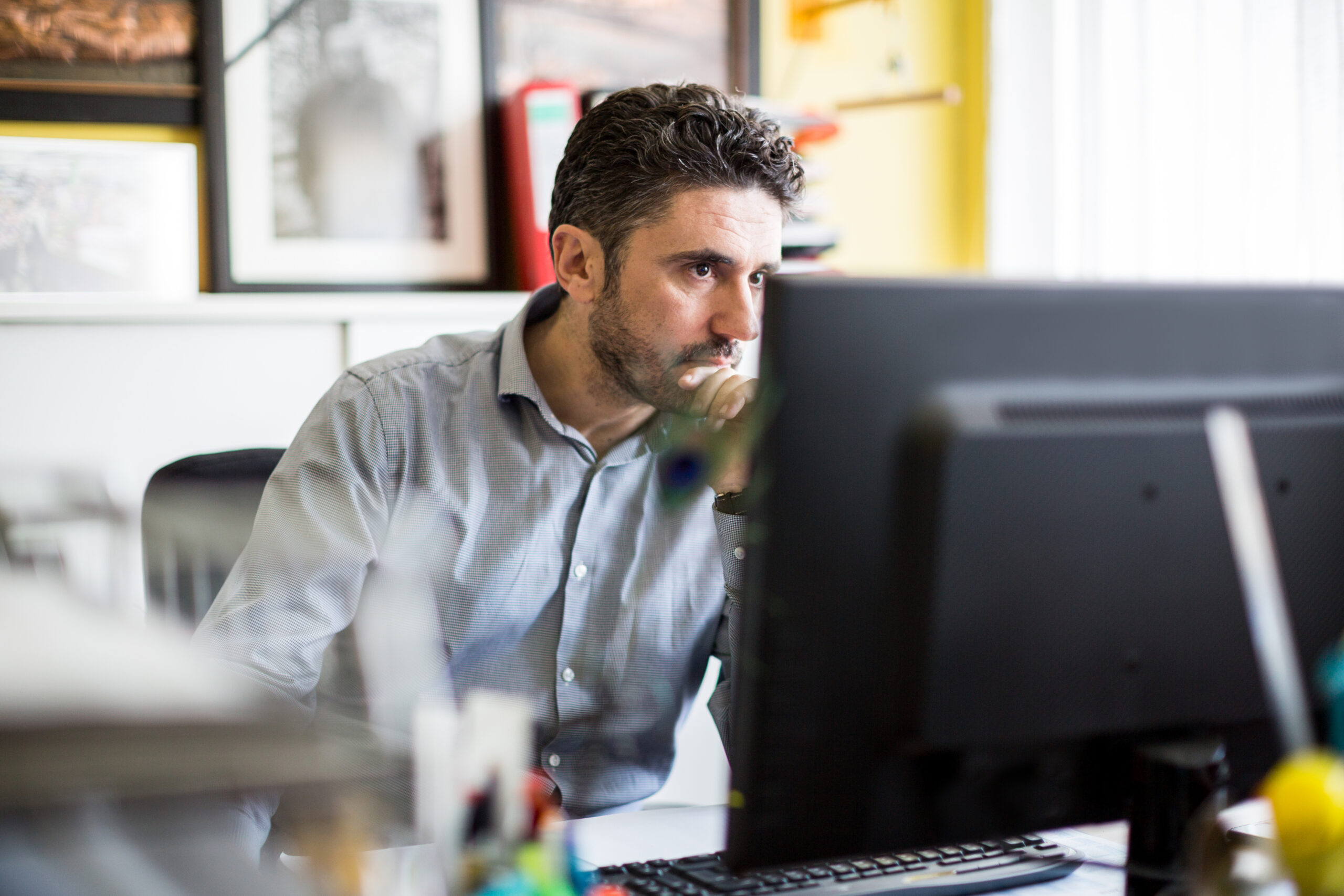 Mature man sitting at his desk and looking at camera with serious expression at textile shop. Textile shop owner working at his desk.